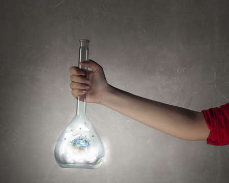 Hand holding glass tube with Earth planet inside. Elements of this image are furnished by NASA
