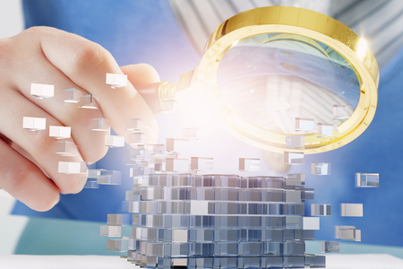 Hands of woman looking in magnifier at 3d illustration cube figureの写真素材