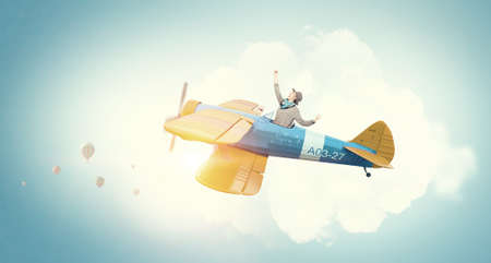 Young funny woman flying in air in retro airplaneの写真素材