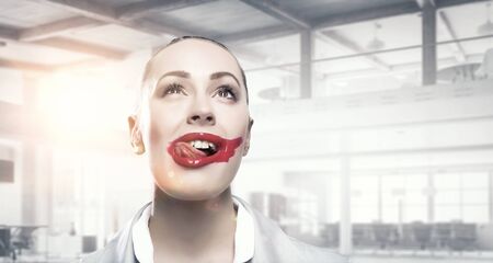 Attractive woman applying red lipstick with brushの写真素材