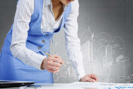 Young attractive businesswoman working at her desk with laptop and construction projectの写真素材