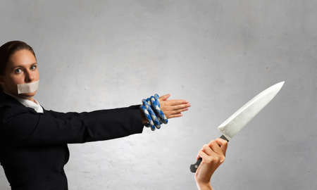 Young businesswoman with tape on mouth and tired handsの写真素材