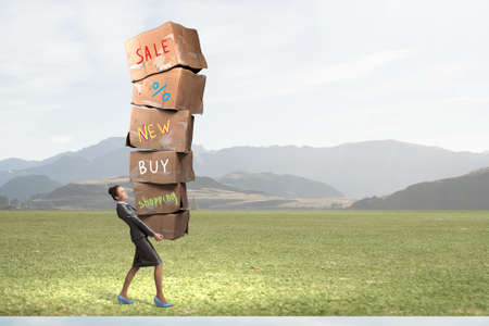Woman in suit carrying stack of carton boxesの写真素材