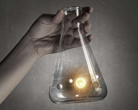 Hand holds flask with image of space planets systemの写真素材