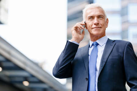 Portrait of confident businessman with his mobile phone outdoorsの写真素材