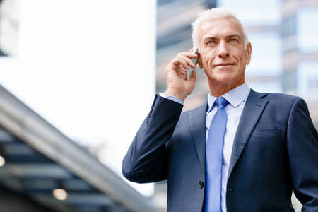 Portrait of confident businessman with his mobile phone outdoors