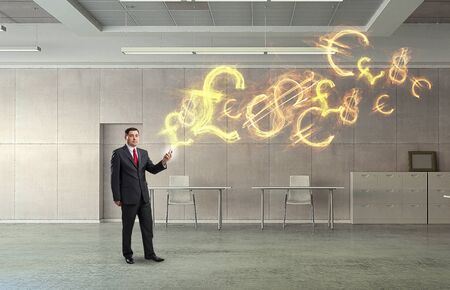 Adult businessman in modern office interior using mobile phoneの写真素材