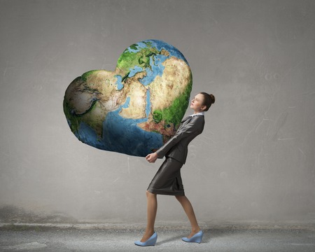 Attractive businesswoman carrying Earth planet in hands. Elements of this image are furnished by NASAの写真素材