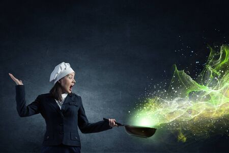 Attractive woman chef in suit with pan in handの写真素材