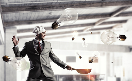 Young man in business suit and cook hat holding panの写真素材