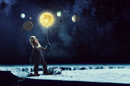 Cute kid boy with carton helmet on head dreaming to become astronaut