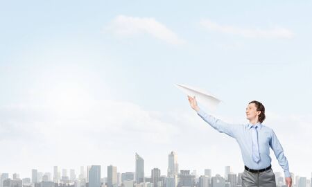 Young businessman with paper plane in handの写真素材