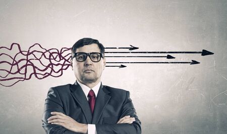 Thoughtful adult businessman with arrows and thoughts coming out of his headの写真素材