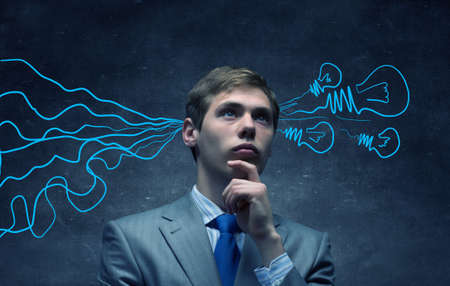 Thoughtful businessman with arrows and thoughts coming out of his headの写真素材