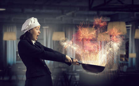 Attractive woman chef in suit with pan in handの写真素材