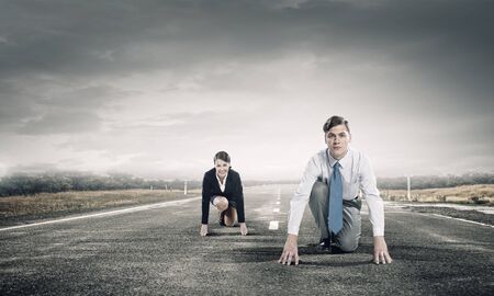 Young determined businesspeople standing in start position ready to competeの写真素材