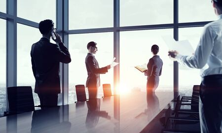 Group of business people working in office in lights of sunsetの写真素材