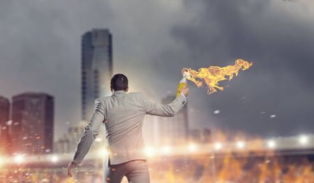 Aggressive businessman in suit throwing burning molotov cocktailの写真素材