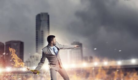 Aggressive businessman in suit throwing burning molotov cocktailの写真素材