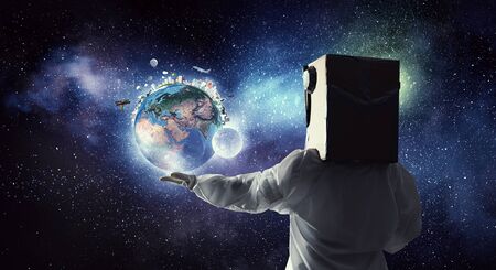 Young woman with carton box on head imagine she is astronaut. Elements of this image are furnished...