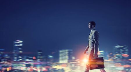 Young elegant businessman against night city backgroundの写真素材