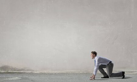 Young determined businessman standing in start position ready to competeの写真素材