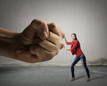 Small woman under pressure of big human handの写真素材