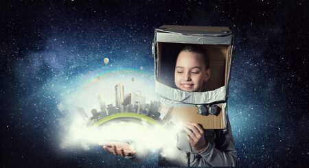 Cute kid girl with carton helmet on head dreaming to become astronaut