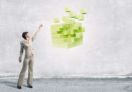 Businesswoman reaching hand to touch 3D rendering cube figureの写真素材