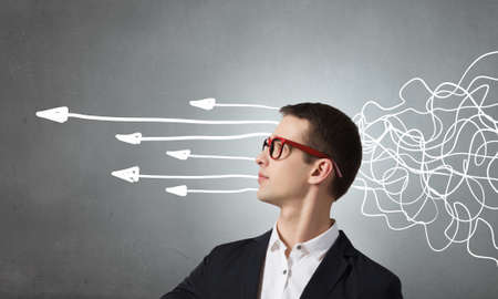 Thoughtful businessman with arrows and thoughts coming out of his headの写真素材