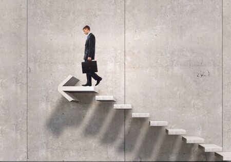 Young businessman reaching up staircase as symbol of growth and progressの写真素材