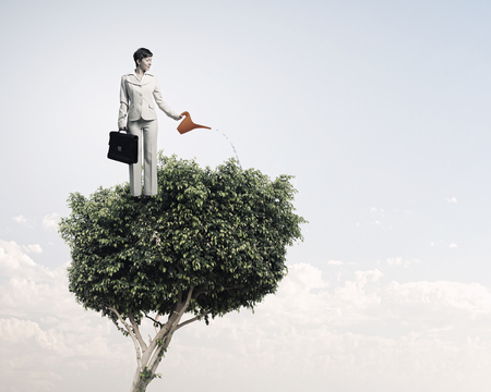 Young businesswoman watering green plant with canの写真素材