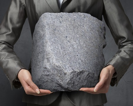 Close view of businesswoman holding big heavy stone