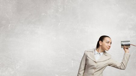 Young businesswoman using tin can and string as communication toolの写真素材