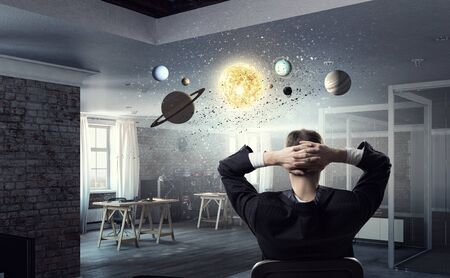 Relaxed businessman at the office sitting back with his hands behind his headの写真素材