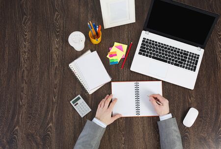 Laptop and office supplies on the wooden table as seen from aboveの写真素材