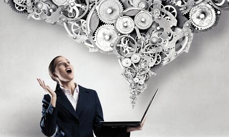 Attractive shocked businesswoman with laptop in hands in modern office interiorの写真素材