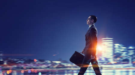 Young elegant businessman against night city backgroundの写真素材