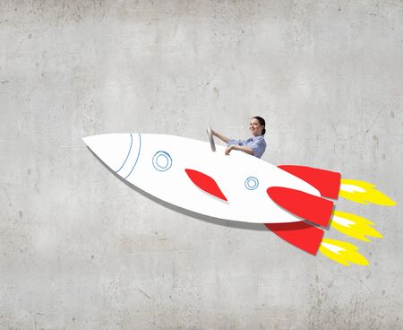 Young happy student girl riding fast drawn rocketの写真素材