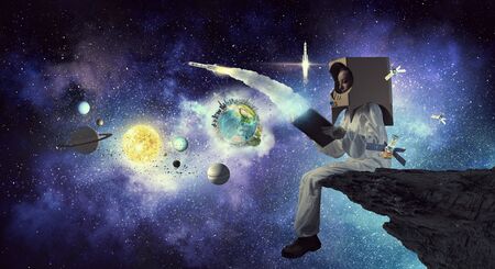 Young woman with carton box on head imagine she is astronaut. Elements of this image are furnished by NASAの写真素材