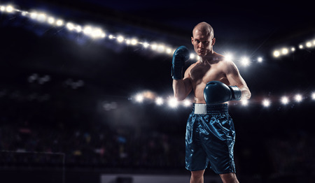 Professional boxer fighting on arena in spotlightsの写真素材