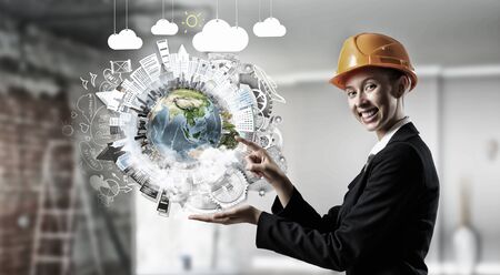 Attractive engineer woman holding in palm Earth planet.