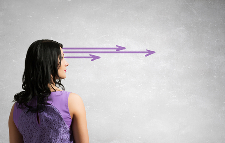 Pretty young woman making decision with arrows coming out of her headの写真素材