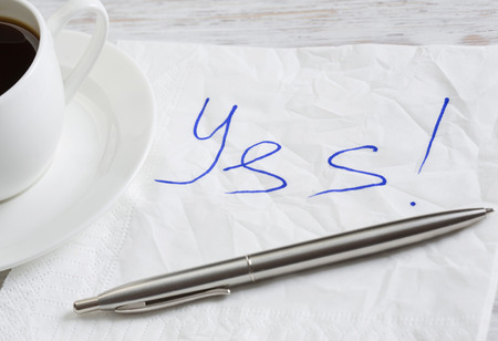 Yes message written on napkin and coffee cup on wooden tableの写真素材