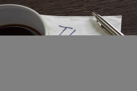 Romantic message written on napkin and cup of coffee on wooden tableの写真素材
