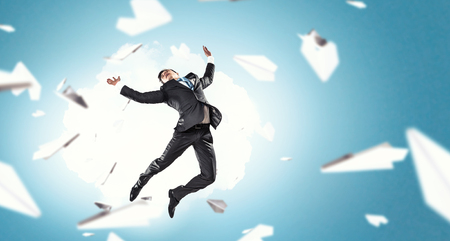 Funny jumping businessman and paper planes flying aroundの写真素材