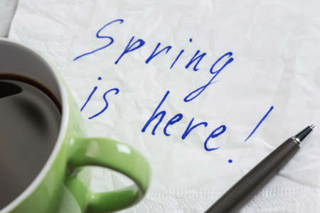 Spring is here message written on napkin and cup of coffeeの写真素材