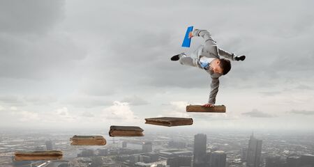 Active businessman making handstand on pile of books