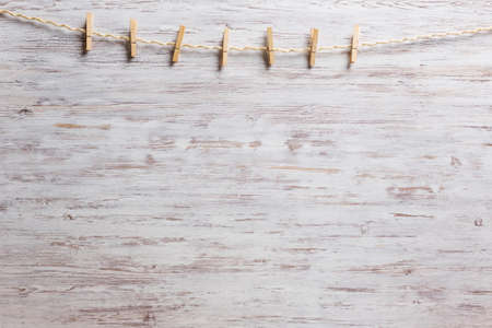 Old clothespins hanging on rope on wooden backgroundの写真素材