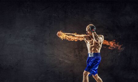 Strong boxer man in gloves against cement wallの写真素材